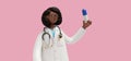 3d rendering. Black woman doctor holds big pill, pharmacist cartoon character, healthcare professional, isolated on pink Royalty Free Stock Photo