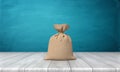 3d rendering of a blank tied up hessian bag full of money standing on a wooden surface on blue background. Royalty Free Stock Photo