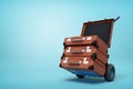 3d rendering of blue hand truck with stack of three brown suitcases on top on light-blue background with copy space.