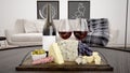 3D rendering of a board with cheese and wine on it with a sofa and pictures on the background Royalty Free Stock Photo
