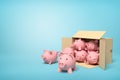 3d rendering of cardboard box lying sidelong full of pink ceramic piggy banks on light-blue background. Royalty Free Stock Photo