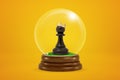 3d rendering of christmas snow globe with black chess pawn wearing golden crown on yellow background. Royalty Free Stock Photo