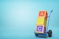 3d rendering of colorful alphabet toy blocks showing `ABC` sign on a hand truck on blue background
