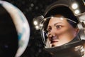 Young female cosmonaut in helmet looking at Earth from space