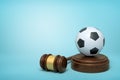 3d rendering of football on sounding block with judge gavel lying beside on light-blue background. Royalty Free Stock Photo