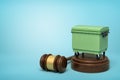 3d rendering of green trash bin on round wooden block and brown wooden gavel on blue background