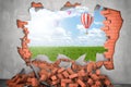 3d rendering of hot air ballon in the sky above green grass seen through a gap in red brick wall