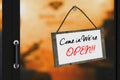 3D Rendering : illustration of Come in were open sign board hanging at the glass door against blurred light at cafe background Royalty Free Stock Photo