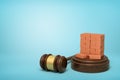 3d rendering of miniatured stack of red bricks on sounding block with gavel lying beside on light-blue background with