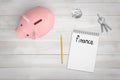 3d rendering of notepad with word `Finance` written in it, pencil, piggy bank, crumpled piece of paper, and keys on