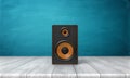 3d rendering of a one black speaker box with orange trim standing on a wooden table in front of a blue background. Royalty Free Stock Photo