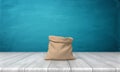 3d rendering of an open money bag made of hessian cloth with no markings standing on a wooden desk on blue background.