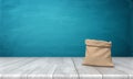 3d rendering of an open money bag made of hessian cloth with no markings standing on a wooden desk on blue background.