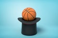 3d rendering of orange basketball ball on black top hat upside down on blue background Royalty Free Stock Photo