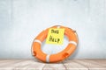 3d rendering of orange life buoy with yellow post-it note `TAKE HELP` on it, lying on wooden floor near concrete wall. Royalty Free Stock Photo