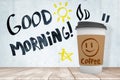 3d rendering of paper coffee cup standing on wooden table near wall with hand-drawn title `Good morning`