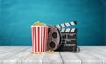 3d rendering of pop corn bucket, film reel, and clapperboard standing on wooden floor near blue wall.