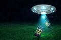 3d rendering of silver metal UFO with black radioactive barrels on dark night sky and green grass background