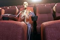 A skeleton in an empty movie theatre representing bored to death and stay at home concepts