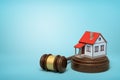 3d rendering of small white house with red roof on round wooden block and brown wooden gavel on blue background Royalty Free Stock Photo