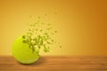 3d rendering of a tennis ball lying on wooden surface and starting to disintegrate on yellow background with much copy Royalty Free Stock Photo