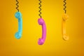 3d rendering of three colorful retro telephone receivers hanging on yellow background Royalty Free Stock Photo