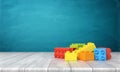 3d rendering of a toy building blocks lying in a colorful pile over a wooden desk on a blue background.