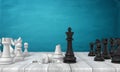 3d rendering of two sets of chess figures standing on a wooden desk where a black kind stands near a broken white one. Royalty Free Stock Photo