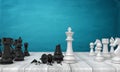 3d rendering of two sets of chess figures standing on a wooden desk where a white kind stands near a broken black one. Royalty Free Stock Photo