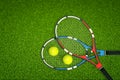 3d rendering of two tennis rackets and two tennis balls as seen from above on a fresh green lawn.