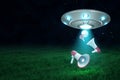 3d rendering of UFO above green field under night sky with three megaphones falling down from its open hatch.