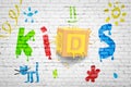 3d rendering of white brick wall with small colorful pictures and big title KIDS with big ABC block smashed into wall Royalty Free Stock Photo