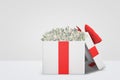 3d rendering of a white gift box with a red bow full of 100 dollar bills on white background. Royalty Free Stock Photo