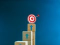 3d target icon on the top of wooden cube blocks, bar graph chart steps with up arrows on blue background. Royalty Free Stock Photo