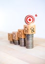 3d target icon on wooden cube block with rise percentage and home icons on money coin stack as growth graph steps. Royalty Free Stock Photo