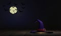 The witch`s hat on the wooden floor of the Halloween festival. The background is a full moon and bats give a scary feeling.Showin