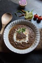 Daal makhni or black lentils soup served in a bowl along with condiments.
