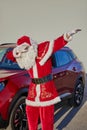 Dabbing Santa Claus against the background of a red car