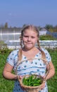 At the dacha, a girl is holding a basket with hot green pepper in her hands. Royalty Free Stock Photo