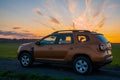 Dacia Duster compact SUV on gravel road at sunset