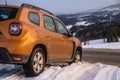 Dacia Duster SUV at the exit of the snowy mountain wilderness on the asphalt path Royalty Free Stock Photo