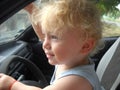 Dad allowed the little boy with fluffy white hair to sit in the car and play the driver. The child is satisfied, looking Royalty Free Stock Photo