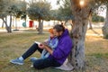 Dad and baby read a book under a tree in the park.