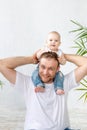 Dad with baby son around his neck having fun on a white background, happy fatherhood and family, father`s day Royalty Free Stock Photo