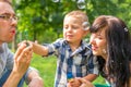 Dad blow soap bubbles and teaches his son. Mom sits by, looks an Royalty Free Stock Photo