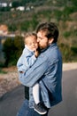 Dad carries and kisses in cheek a little girl in his arms, standing on the road. Close-up Royalty Free Stock Photo