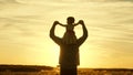 Dad carries on shoulders of his beloved child, in rays of sun. Father walks with his daughter on his shoulders in rays Royalty Free Stock Photo