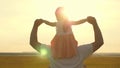 Dad carries on shoulders of his beloved child, in rays of sun. Father walks with his daughter on his shoulders in rays Royalty Free Stock Photo