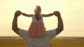 Dad carries on shoulders of his beloved child, in rays of sun. Father walks with his daughter on his shoulders in rays Royalty Free Stock Photo