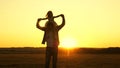 Dad carries on shoulders of his beloved child, in rays of sun. Father walks with his daughter on his shoulders in rays Royalty Free Stock Photo